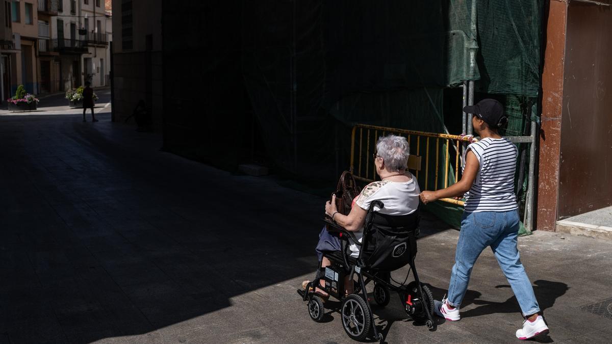Una cuidadora pasea a una anciana en silla de ruedas