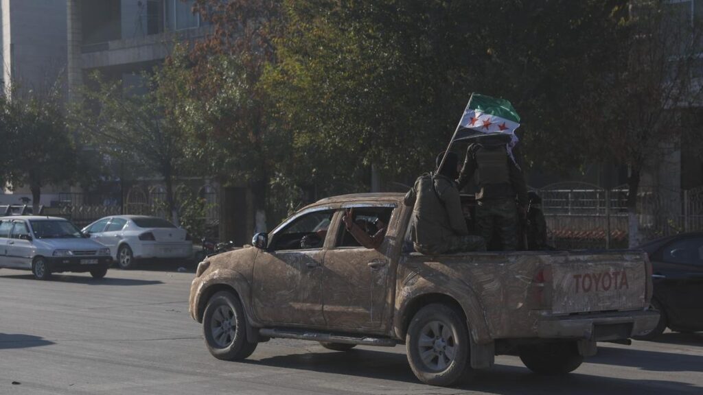 Un coche con milicianos sirios portando la bandera de la revolución patrulla por las calles de Alepo.