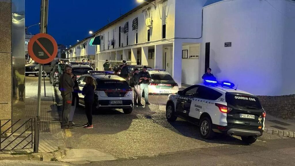 Vecinos y vehículos policiales en la calle donde ha ocurrido el suceso, que permanece acordonada.