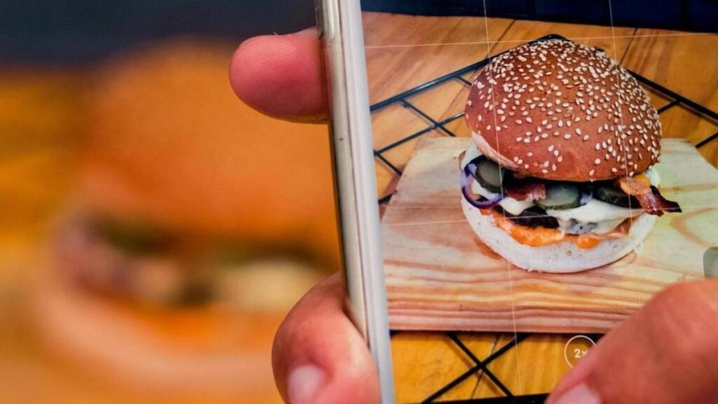 Una persona le saca una foto a una hamburguesa.