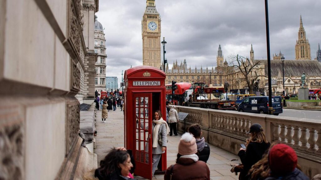 Turistas hacen cola para fotografiarse en una cabina londinense frente al Big Ben.