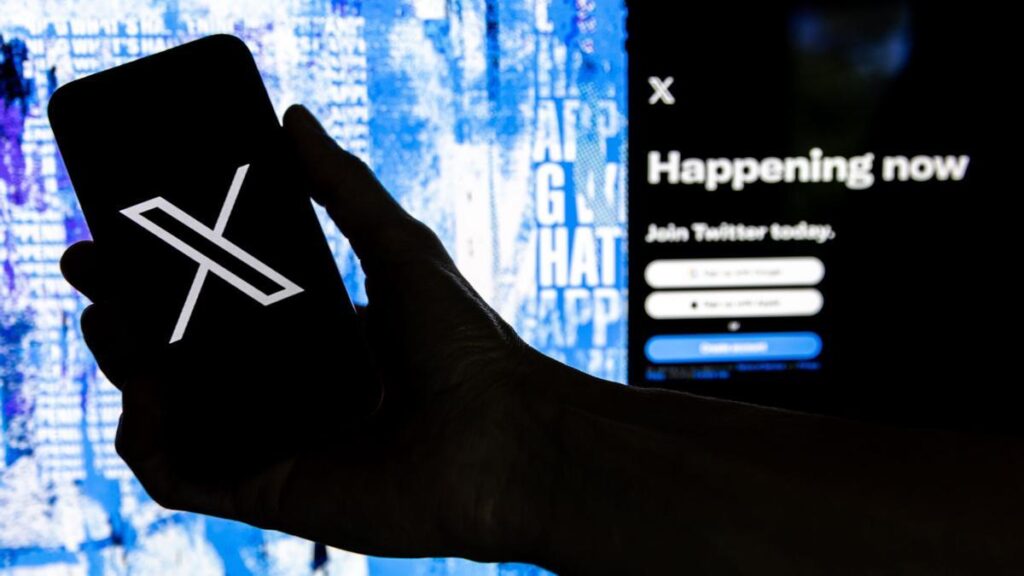 Una persona sosteniendo un teléfono móvil con el logotipo de la página 'X'.