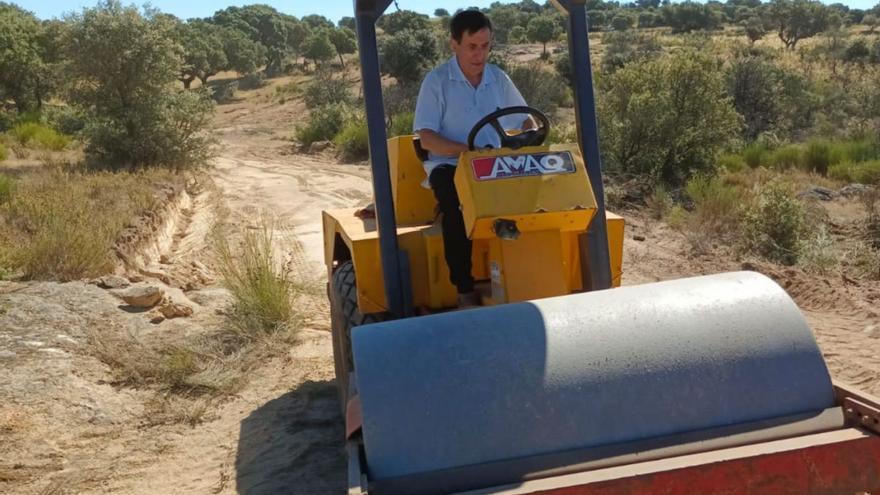 Domingo Pérez Alonso con una apisonadora nivela un camino rural.