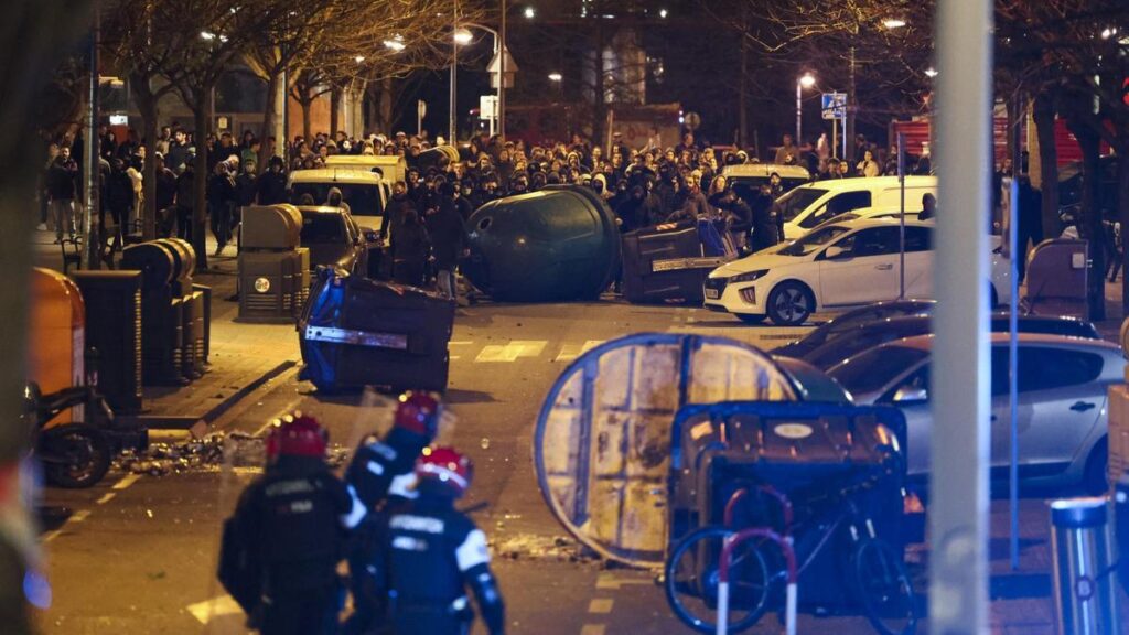 Manifestantes vuelcan contenedores frente a los agentes de la Ertzaintza.