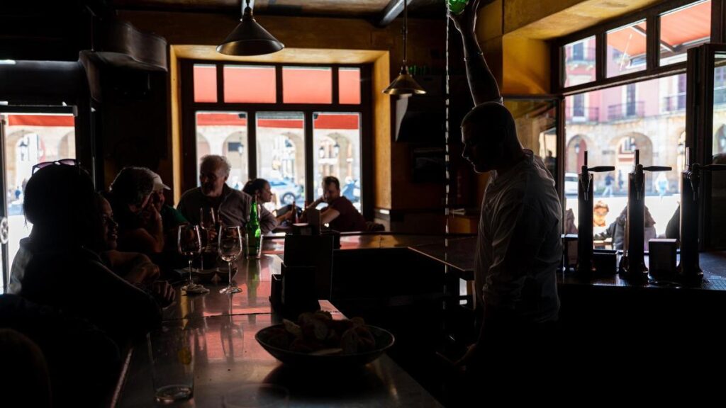 Un camarero sirve sidra en un bar durante el apagón en Gijón.