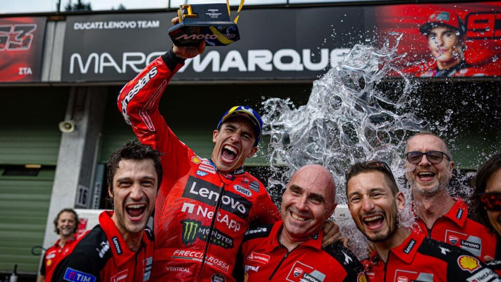 Marc Márquez, eufórico, está a punto de recibir una ducha, un cubo inmenso, de agua como celebración en Brno.a,