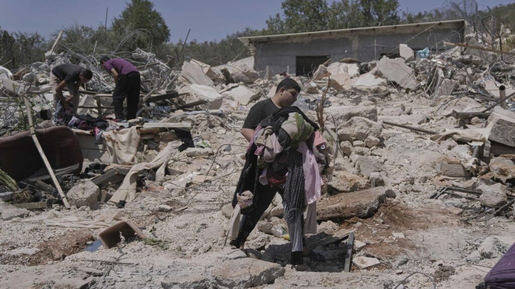 Un joven palestino recupera ropa de los escombros de su casa demolida por Israel en el pueblo de Beit Sira, cerca de Ramala, este martes.
