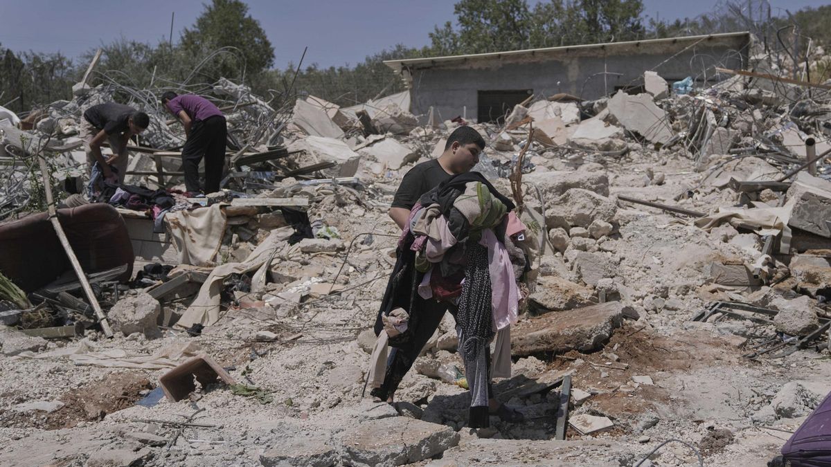 Un joven palestino recupera ropa de los escombros de su casa demolida por Israel en el pueblo de Beit Sira, cerca de Ramala, este martes.