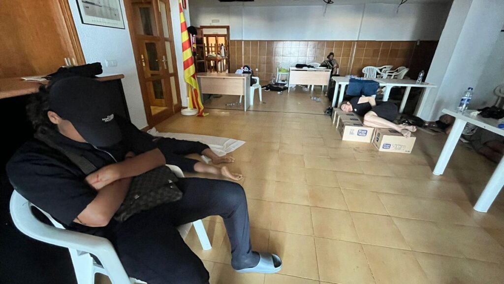 Uno de los recién llegados a Formentera descansa sobre unas cajas de cartón en un local de la Savina