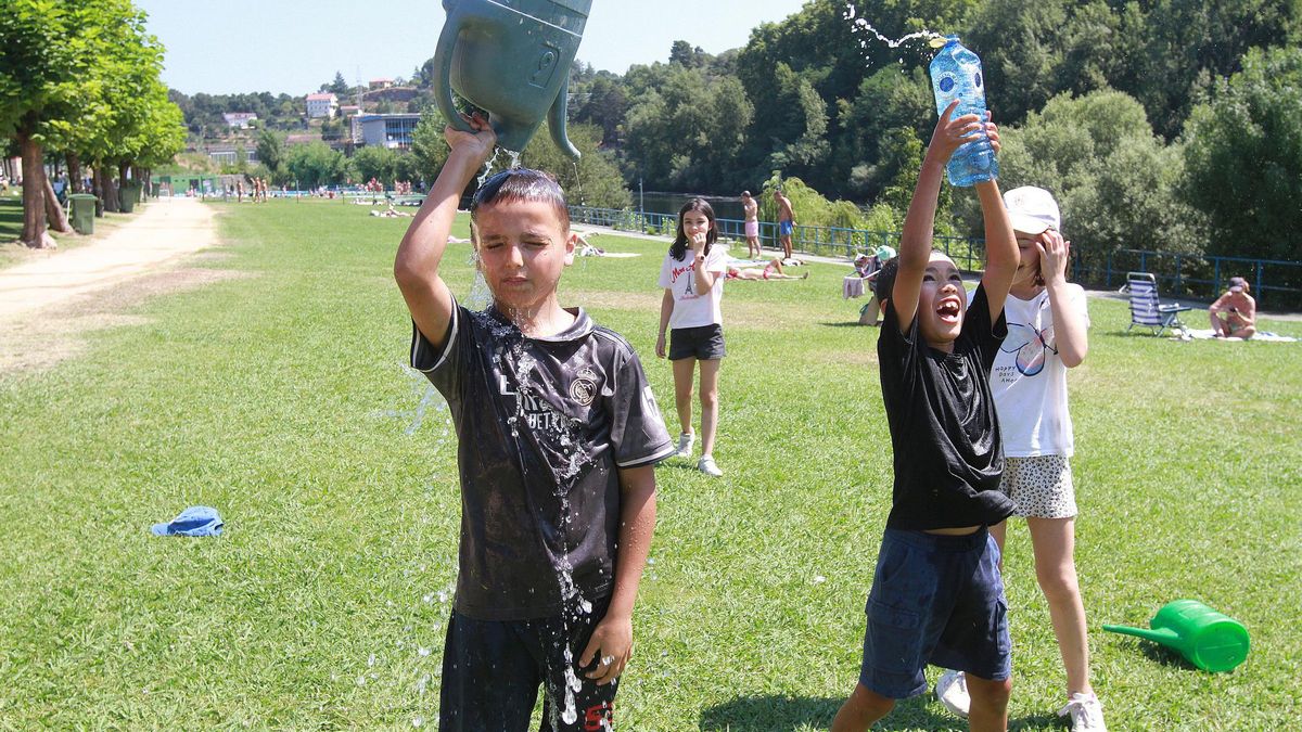 Niños refrescándose con regaderas y botellas en Ourense.