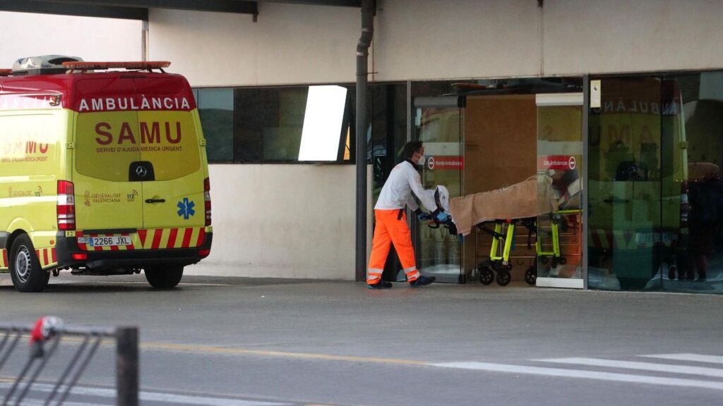 Un técnico sanitario entra con una persona trasladada en una ambulancia SAMU en urgencias del Hospital La Fe.