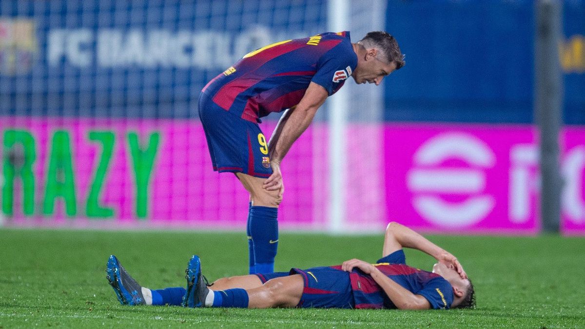 Fermín, tendido en el césped, con Lewandowski mostrando su preocupación.