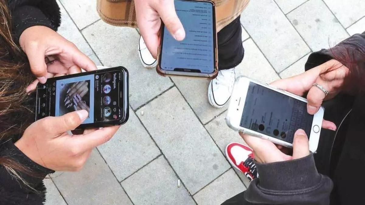 Jóvenes utilizan su móvil para navegar en redes sociales