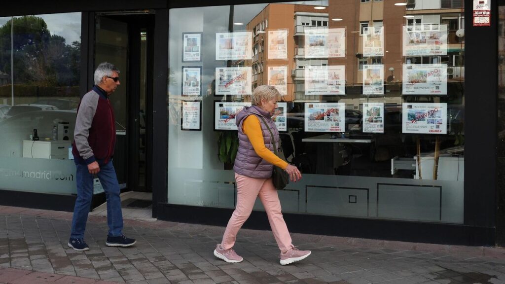 Una mujer pasa frente al escaparate de una inmobiliaria.