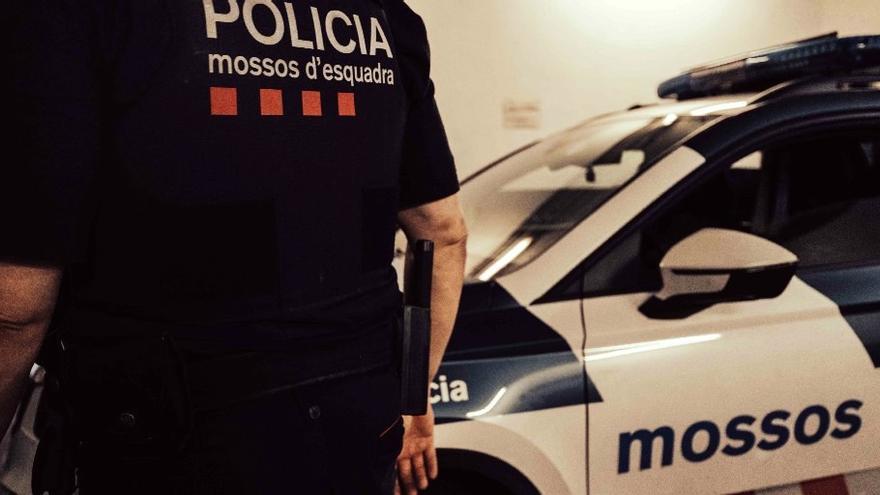 Un agente de los Mossos d'Esquadra junto a un vehículo policial.