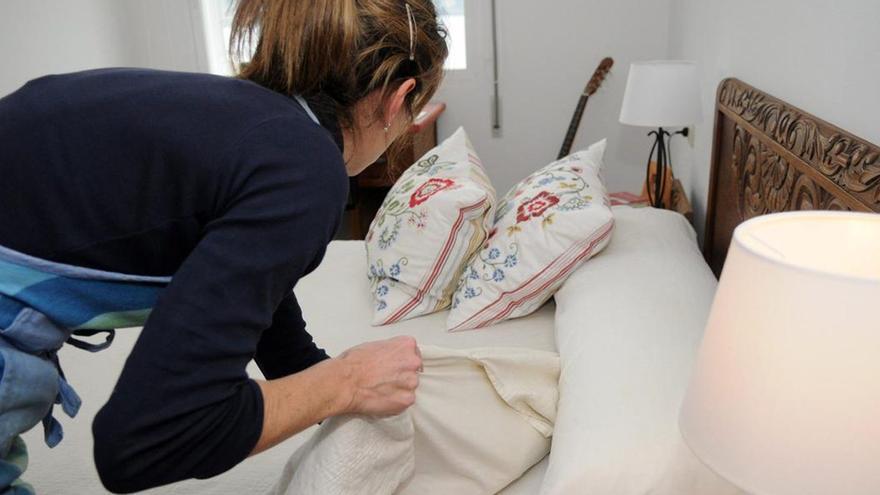 Una empleada del hogar haciendo una cama.