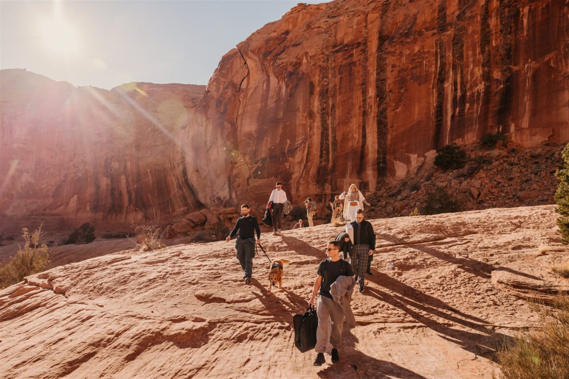 Les invités de l'évasion parcourent un sentier rocheux jusqu'à Corona Arch pour la cérémonie de mariage à Moab