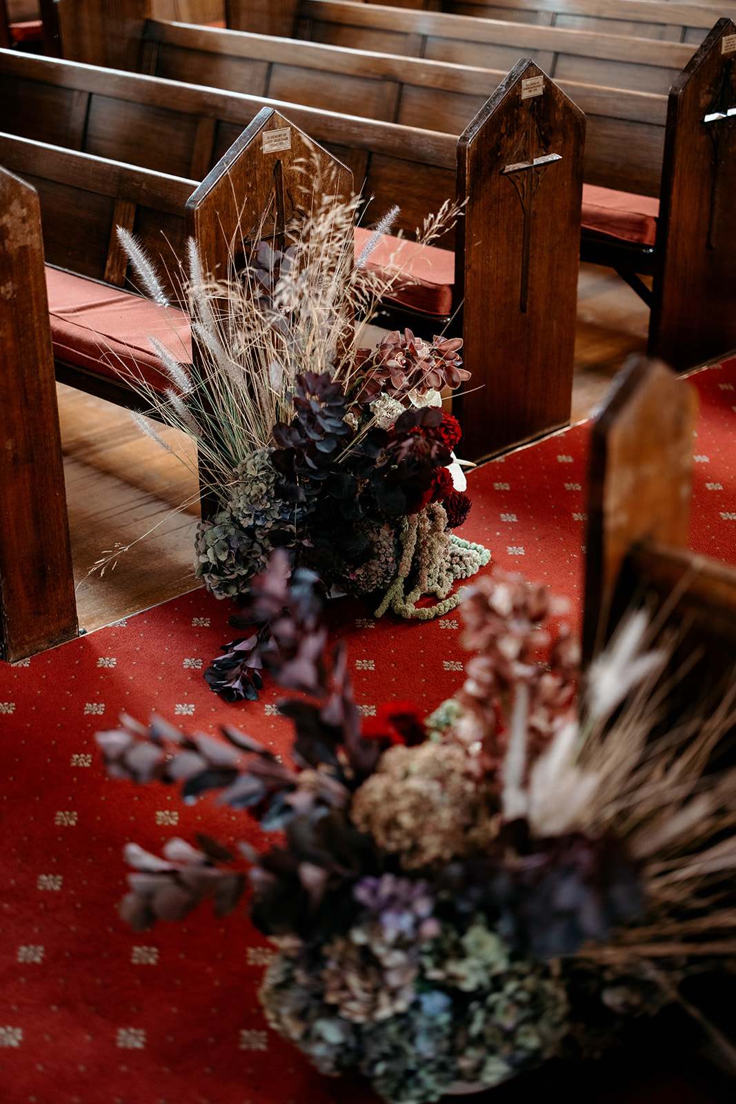 Arrangement floral séché et frais pour cérémonie dans des tons bordeaux, blush et poussiéreux, décoré le long des bancs d'église lors d'un mariage libanais à Melbourne – fleurs de The Beautiful Bunch, photographie de Kinship de Kristy